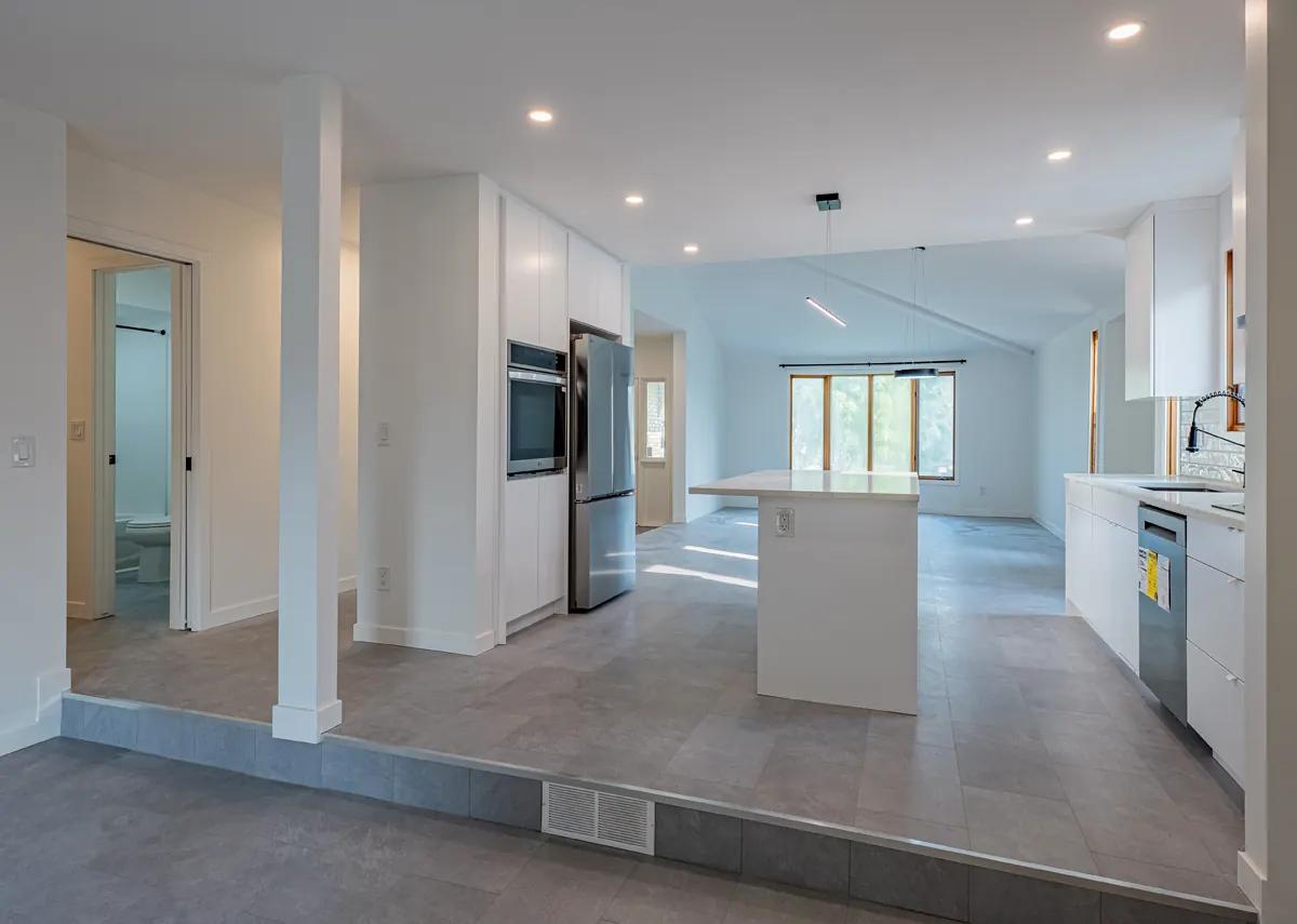 The kitchen and island from the step below, windows across the far end