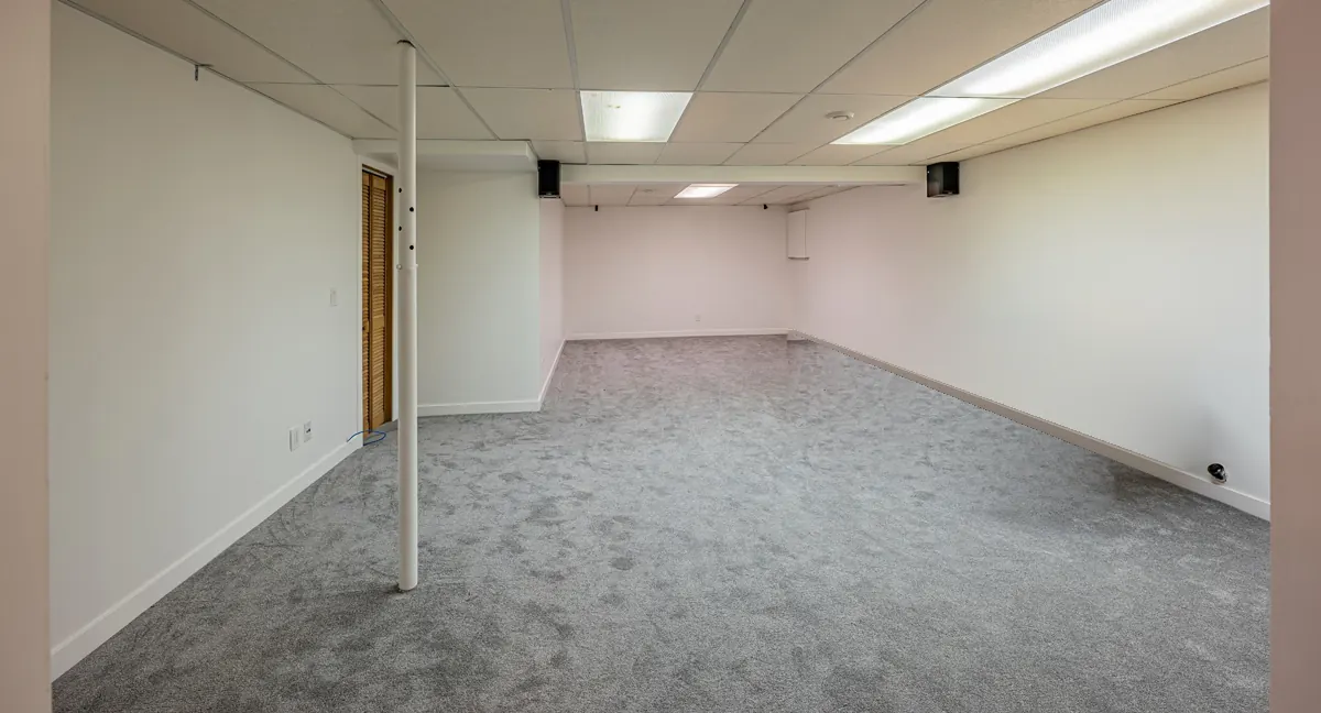 The open basement room, new carpet and white walls under a drop ceiling