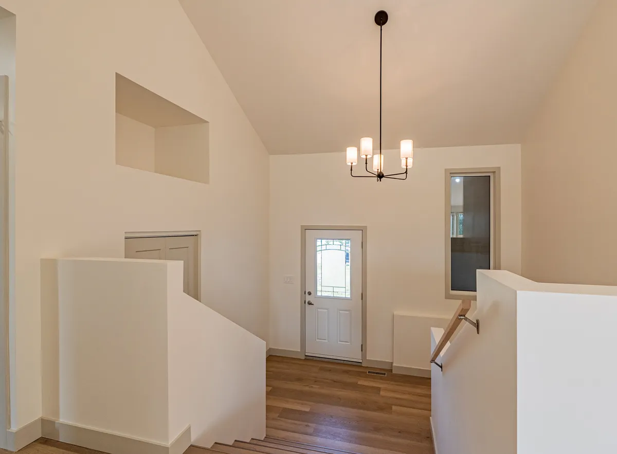 The stair up to the front door, a chandelier hung in the peaked entry