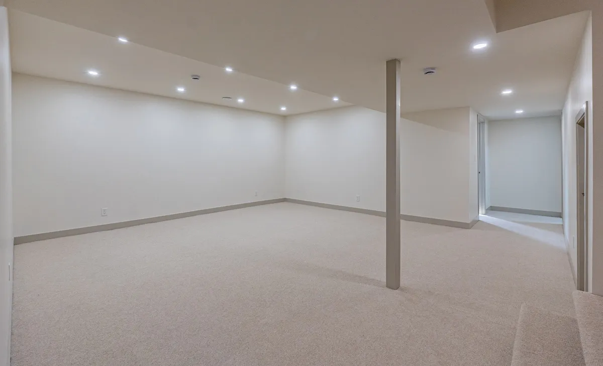 The finished basement, an open carpeted room under pot lights