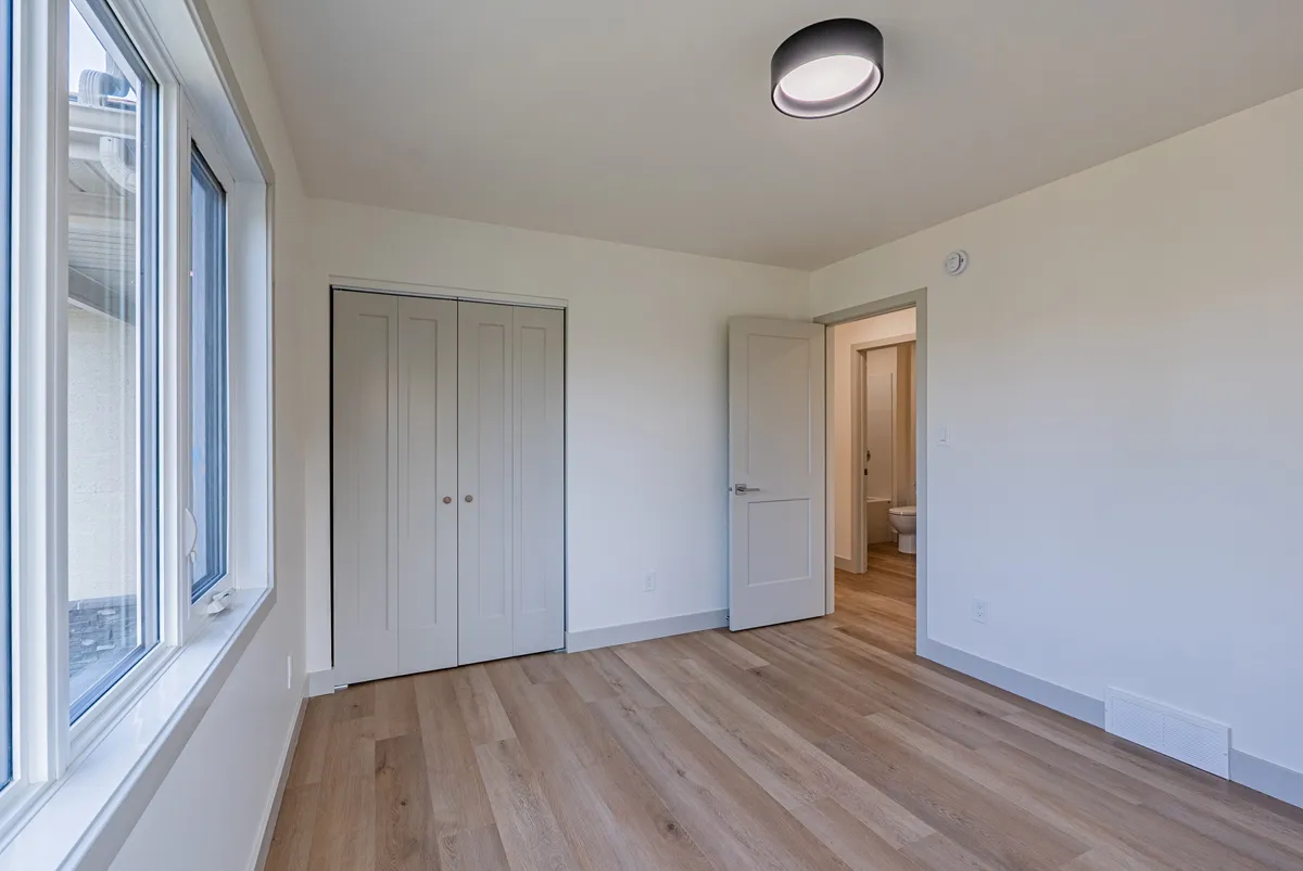 A bedroom at an angle, its double closet and the door through to the hall