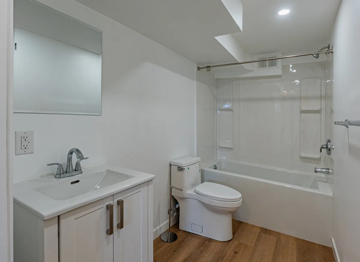 Suite bathroom with a white vanity, framed mirror and a tub-shower