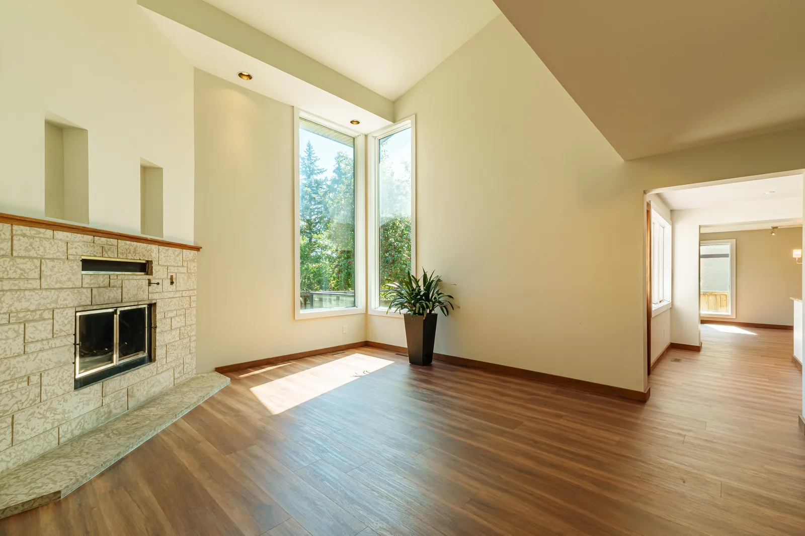 An older Winnipeg home refinished — its stone fireplace kept in place, new plank floor laid up to the hearth